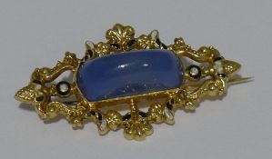 An antique yellow metal enamelled brooch set with chalcedony