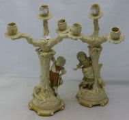 A pair of figurally mounted porcelain candelabra