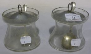 Two silver topped clear glass preserve jars with silver spoons