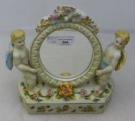 A porcelain cherub mounted mirror
