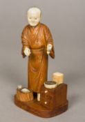 A Japanese Meiji period ivory and wood okimono Formed as an elderly gentleman wearing a gilt