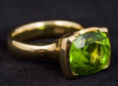 An 18 ct gold peridot set ring With large single facet cut stone. 1 cm high.