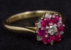 An 18 ct gold diamond and ruby set cluster ring Size M, cased.