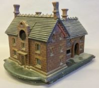 A late 19th/early 20th century watch stand Modelled as a red brick house. 43 cm long.