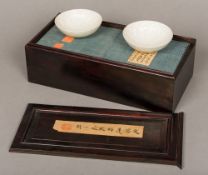 A pair of Chinese Ding ware bowls Each with lotus flower moulded interiors and housed in a fitted