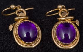 A pair of Victorian unmarked gold amethyst set earrings The closed back stone cabochon cut.