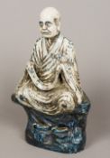 A Chinese blue and white pottery figure Modelled as a robed male seated cross legged on a rocky