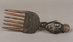 An African tribal carved wooden comb The handle of female mask form. 26 cm long.