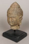 A carved stone bust of the Buddha Typically modelled, standing on a later ebonised display plinth.