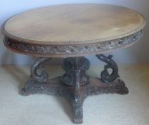 A 19th century Anglo-Indian padouk tilt-top centre table The lappet carved hinged oval top above