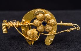 A 15 ct gold sapphire set brooch Formed as a horseshoe and riding crop entwined with a flower. 5.