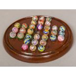 A Victorian painted treen solitaire board Together with a complete set of coloured airtwist marbles.