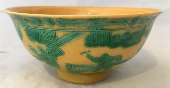 A Chinese porcelain bowl Worked in green with figures in a continuous fenced garden on a yellow