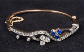 An unmarked gold diamond and sapphire bracelet Of shaped bangle form,