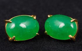 A pair of unmarked gold mounted jadeite stud earrings Cabochon cut. Approximately 1.4 cm wide.