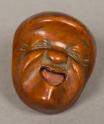 A 19th century Japanese carved boxwood netsuke Formed as a mask,