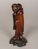 A 19th century Chinese carved wooden immortal Modelled holding a large flower,