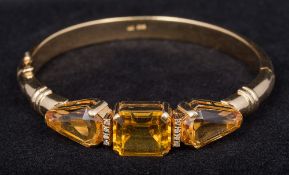 A 14 ct gold diamond and topaz set bangle The central stone emerald cut. 7 cm diameter.