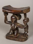 An African carved wooden tribal headrest Of typical curved form,