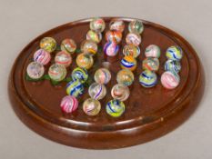 A Victorian painted treen solitaire board Together with a complete set of coloured airtwist marbles.