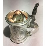 A 19th century engraved glass stein with a finely painted porcelain lid