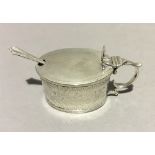 A silver mustard pot with blue liner and silver spoon