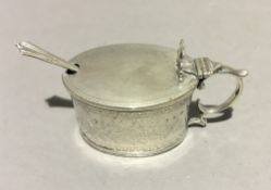 A silver mustard pot with blue liner and silver spoon