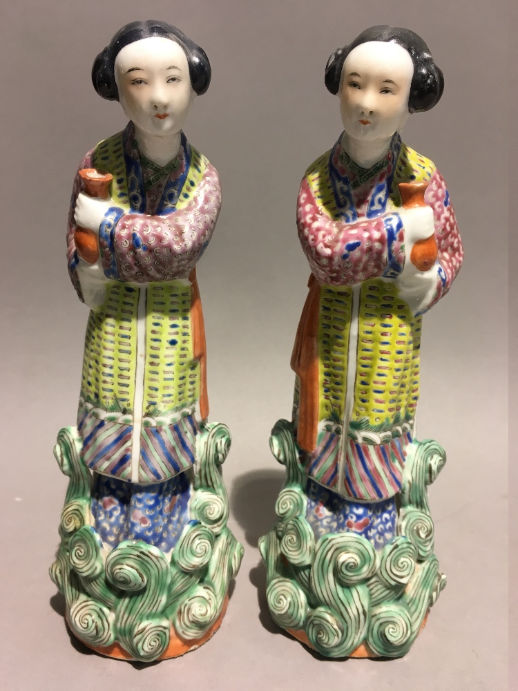 A pair of mid 20th century Chinese porcelain figures of two maidens each holding urns