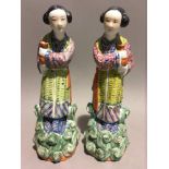A pair of mid 20th century Chinese porcelain figures of two maidens each holding urns