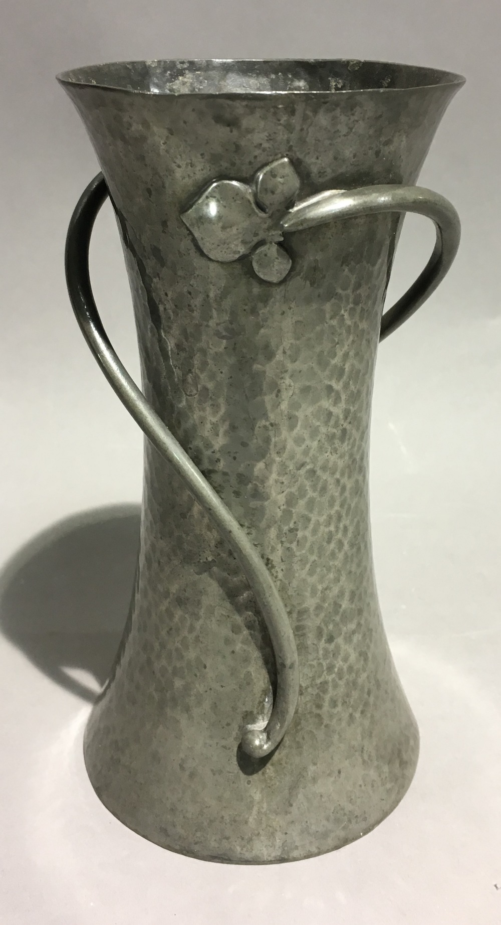 An English pewter Arts and Crafts vase of waisted form and applied flower stems