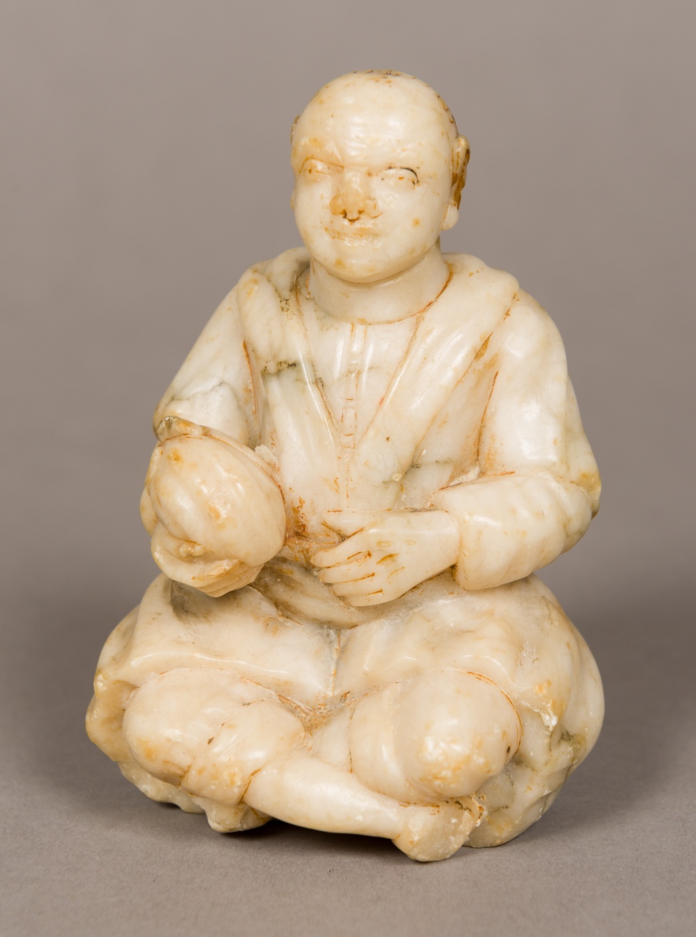 A 19th century Oriental soapstone figure Modelled as a seated gentleman, holding a gourd.