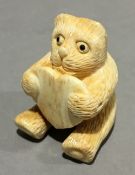 A bone netsuke formed as a kitten holding a heart