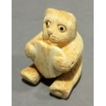 A bone netsuke formed as a kitten holding a heart