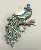 A enamel brooch formed as a peacock inset with mother-of-pearl