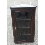 An early 20th century glazed oak corner cupboard