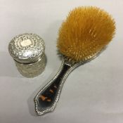 A silver topped jar and a silver and tortoiseshell brush