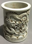 A Chinese white porcelain brush pot decorated with a dragon