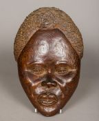 An African carved hardwood female mask Naturalistically worked; together with another Eastern mask.