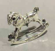 A miniature silver rocking horse