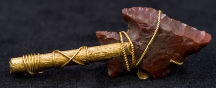 An unmarked gold and flint bar brooch Of pre-historic arrow form. 5 cm long.