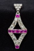 An Art Deco platinum, diamond and ruby pendant Of pierced lozenge form. 5 cm high.