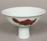 A Chinese porcelain stem cup The bowl decorated in iron red with stylised fish. 17.5 cm diameter.