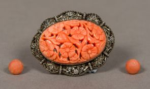 An unmarked silver filigree mounted coral brooch Of pierced floral form;