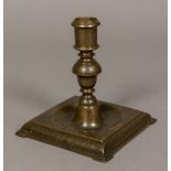 A 17th century European bronze candlestick Finely decorated, standing on a dished square foot.