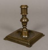 A 17th century European bronze candlestick Finely decorated, standing on a dished square foot.