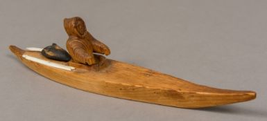 A carved pine model of an Inuit huntsman in a kayak The back of which mounted with two bone hunting