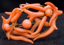 An unmarked gold and coral brooch Of intertwined pierced domed form. 6 cm wide.