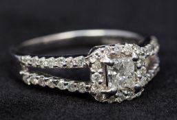 A 14 ct white gold diamond set halo cluster ring The central emerald cut diamond above the pierced