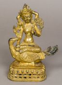 A Sino-Tibetan gilt bronze figure of a multi-armed deity Modelled seated atop a fantastical bird,