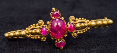 A Victorian unmarked gold and ruby bar brooch Centrally set with five cabochon rubies. 4 cm long.